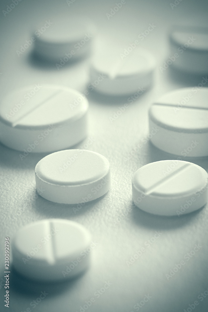 Close-up view of few white pills (tablets). Toned. Selective focus.