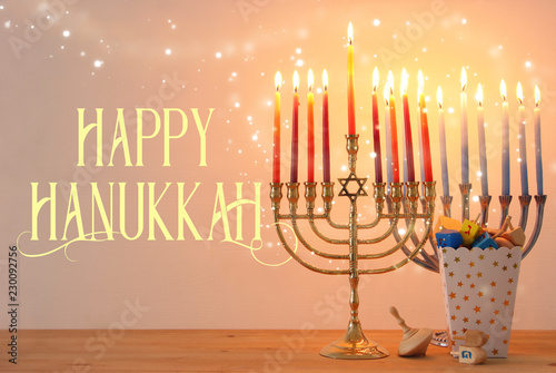 Image of jewish holiday Hanukkah background with traditional spinnig top, menorah (traditional candelabra) and burning candles.