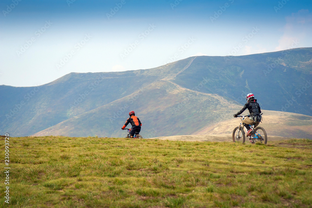 Professional cyclists riding the downhill mountain bike on the mountain trail. Two cyclists are preparing to ride mountain bike on single trail in Carpathians, Borzhava, Ukraine. 21 August, 2018.