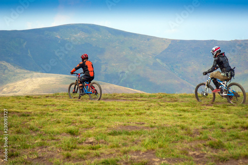 Professional cyclists riding the downhill mountain bike on the mountain trail. Two cyclists are preparing to ride mountain bike on single trail in Carpathians, Borzhava, Ukraine. 21 August, 2018.