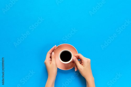 Minimalistic style woman hand holding a cup of coffee on background. Flat lay, top view