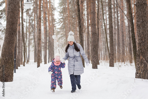 Family, children and nature concept - Mother with daughter have fun in the winter park © satura_