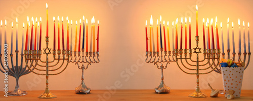 Image of jewish holiday Hanukkah background with traditional spinnig top, menorah (traditional candelabra) and burning candles.