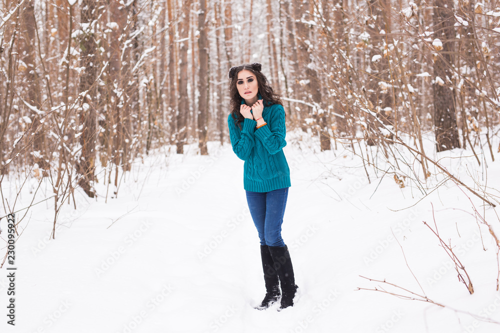 Beautiful young woman walking in the winter snowy nature