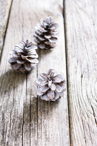 three white painted pine cones Christmas decoration on old rustic wooden table background