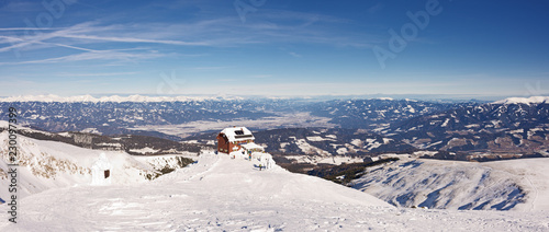 Picturesque winter landscape panorama with high snowy mountains and alpine hut under sunny skies. Panoramic view from top of Styrian mountain Zirbitzkogel, Steiermark, Austria.
