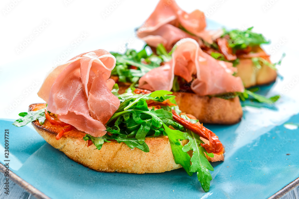 Tasty savory Italian appetizers, or bruschetta, on slices of toasted baguette garnished with basil
