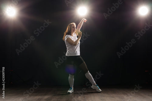 People and dance concept - Young woman dancing jazz funk over dark background © satura_