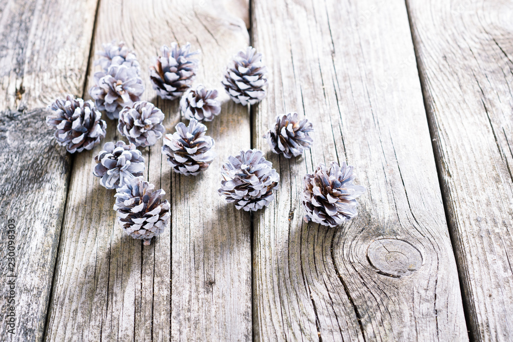 white painted pine cones Christmas decoration on old rustic wood table background