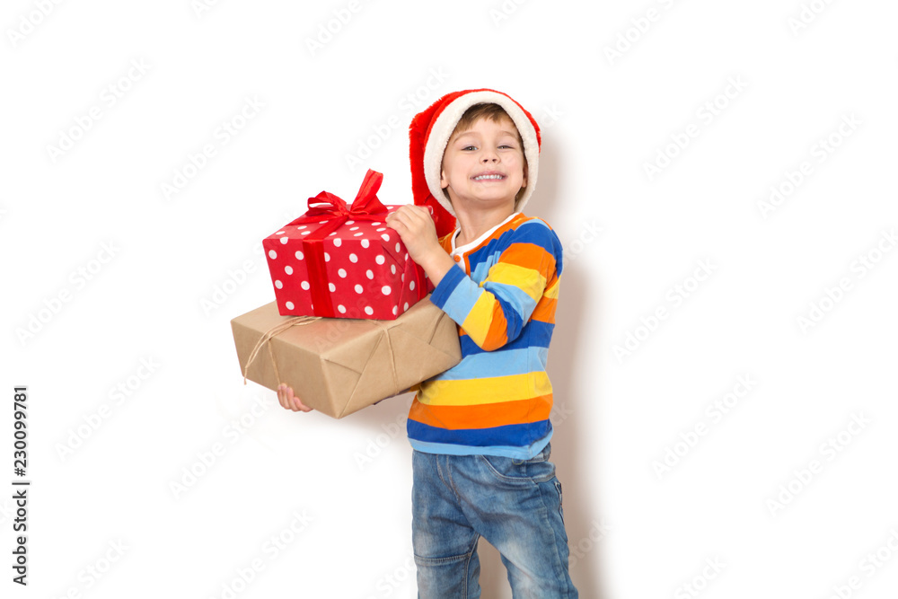 Happy child in Santa red hat holding Christmas presents on a white background. Christmas time.
