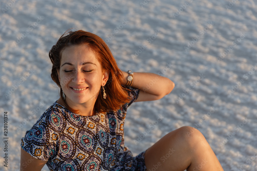 happy smiling girl enjoying the sunset sun and shakes her head, sits on the salt happy smiling girl enjoying the sunset sun and shakes her head, sits on the salt