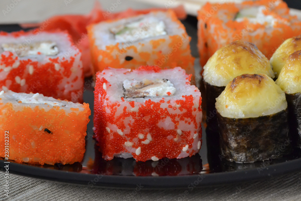 Sushi and rolls on a black plate with chopsticks. Sushi and rolls on a black plate with chopsticks.