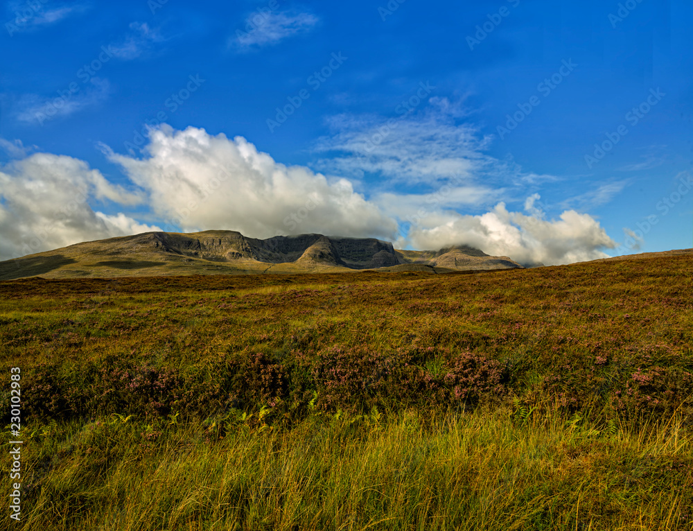 Blue sky with clouds behind a landscape in the highlands