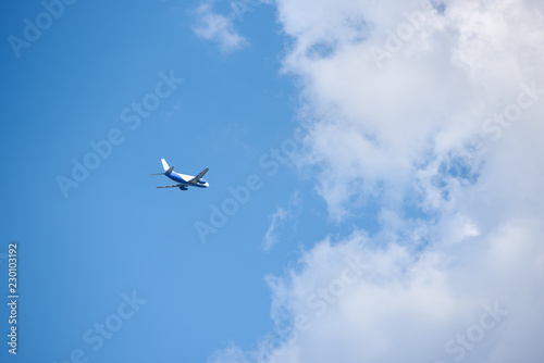 Passenger airplane gain altitude against blue sky and white clouds. © Artem