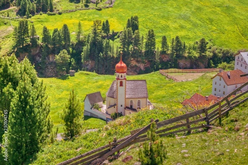 Tyrolean church in a mountainous sunny valley with blooming meadows photo