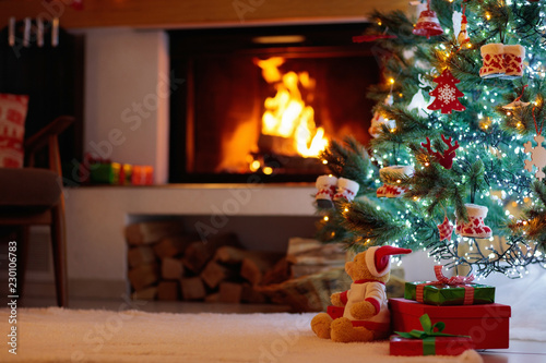 Christmas tree with presents at fire place.