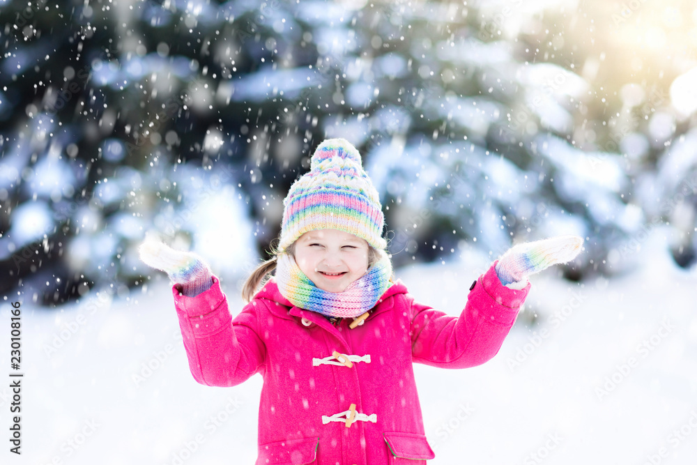 Child playing with snow in winter. Kids outdoors.