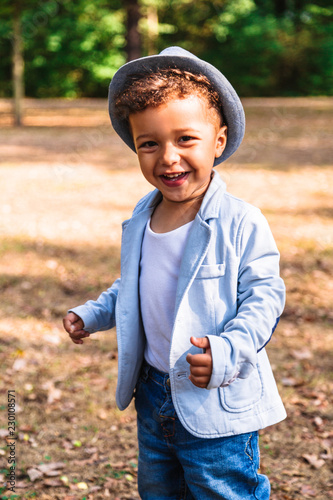 Fotografie Portrait of little smiling boy in hat and jacket outdoors