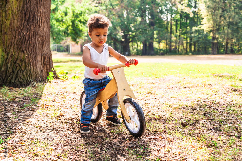 Afro-american or latin little boy ride bicycle in park Afro-american or latin little boy ride bicycle in park