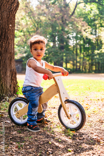 Fototapeta Naklejka Na Ścianę i Meble -  Afro-american or latin little boy ride bicycle in park
