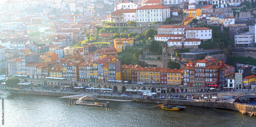 Obraz premium Panorama of the Ribera from the opposite riverside of the river Douro, Porto, Portugal. Colorful houses on the embankment. Wooden barrels of port on boats.