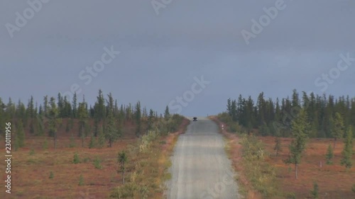 Car Rides on Road among Tundra.	Dirt road in the tundra in autumn.
