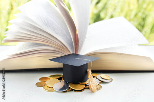 Graduation Cap for savings coins for scholarships for funding and education. Graduation microcline and gold coins and book on a green background, the concept of investment education, closure, photo
