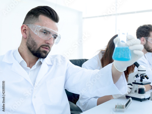 biochemist with flask Petri sitting at a Desk