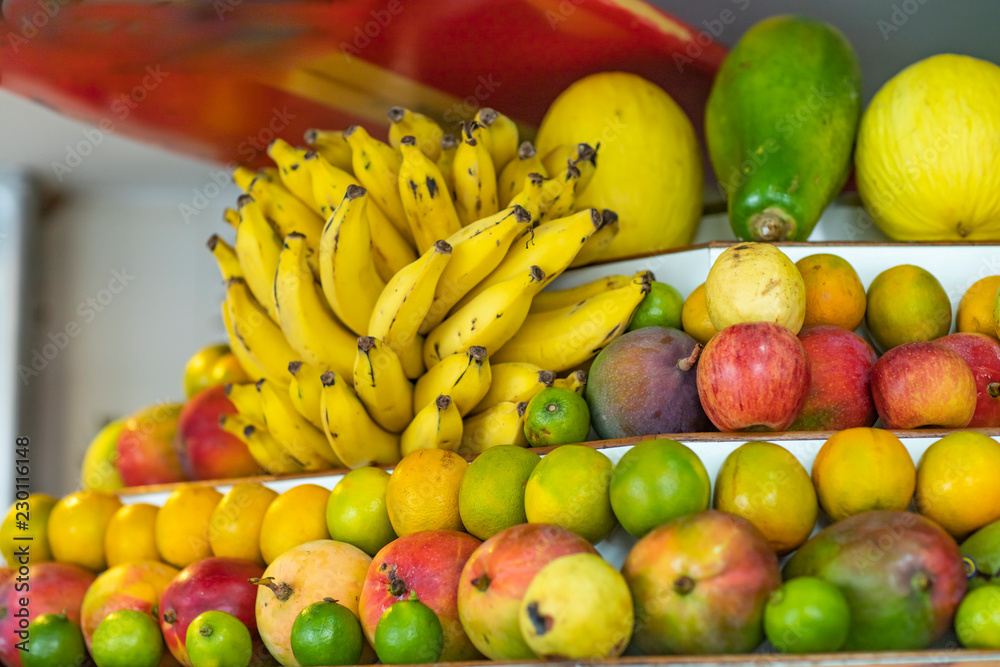 Fresh healthy fruits on shelves in supermarket. Background from banana,apples,melon,papaya,apple,orange,guava,lemon,mango 