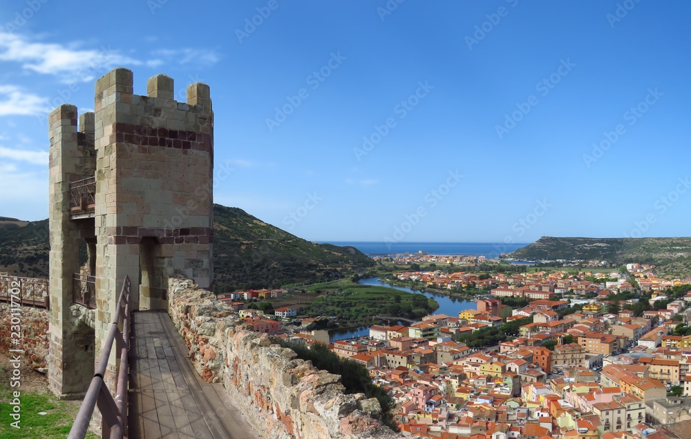 One of the seven towers of the Serravalle caste looking out over the winding river and the old village of Bosa with colourful houses and red roofs, Sardinia, Italy