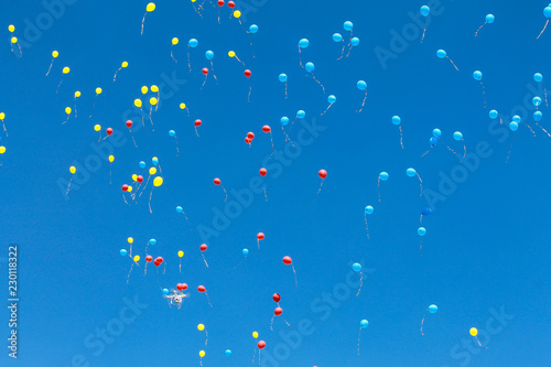 Bright blue, red and yellow air balloons rise up in the blue sky. Balls background, aerostat.