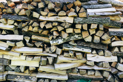 Natural firewood lying in a pile outdoors. Wood background texture. Eco friendly wallpaper.