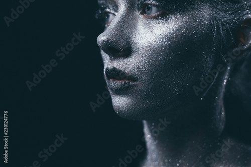Portrait of beautiful woman with silver sparkles on her face. Fashion model with colorful make-up.