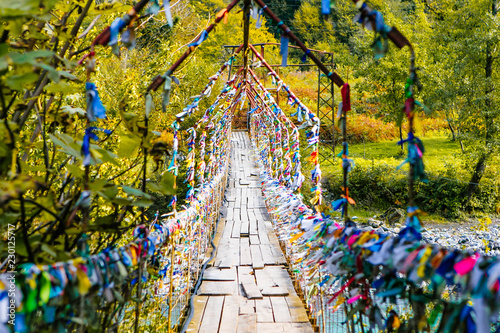bridge over the mountain river with colored flags photo
