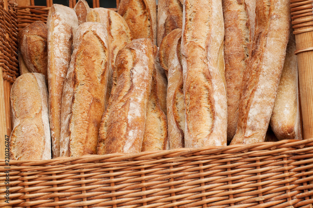several fresh white baguettes in a basket on the counter in a store or on the market