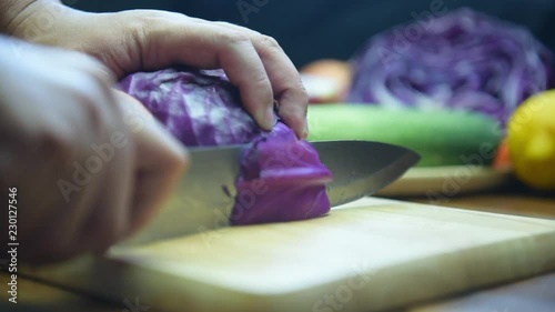 cutting purple cabbage on chopping board. Hand slicing a purple cabbage with a knife.