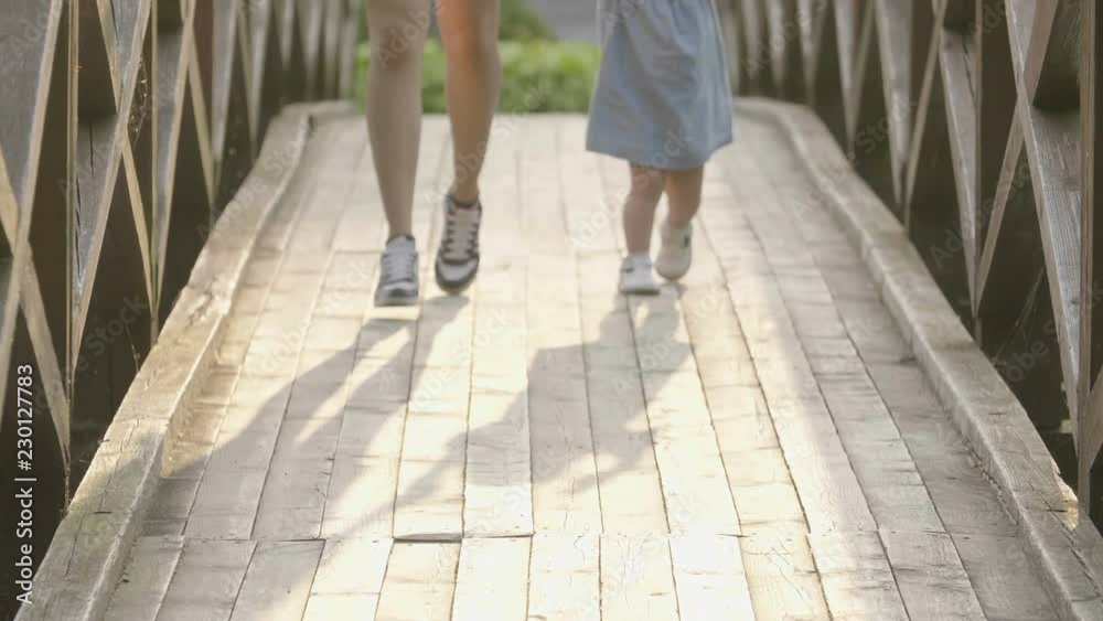 Baby with mom are running on a wooden bridge in the sunset light. Slow motion. Backlight sunset light. Happy family concept. Woman with long hair. Baby with mom are running on a wooden bridge in the sunset light. Slow motion. Backlight sunset light. Happy family concept. Woman with long hair.