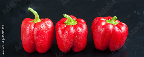 Red sweet pepper on a dark background. Fresh whole red bell pepper with droplets of water.