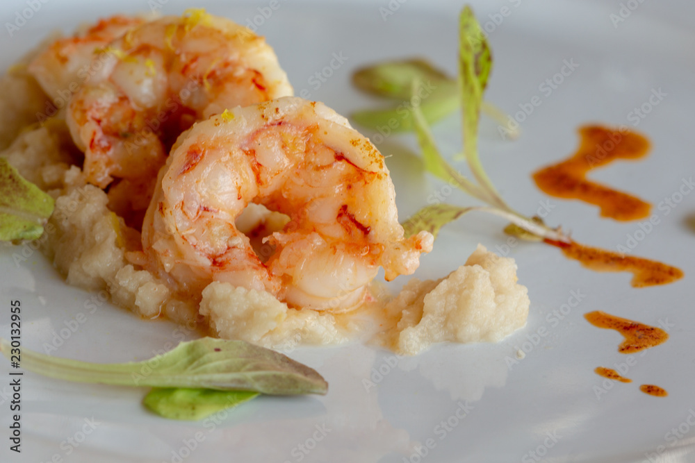 cooked shrimps on a white plate with tomato sauce on the side in a zigzag pattern cooked shrimps on a white plate with tomato sauce on the side in a zigzag pattern