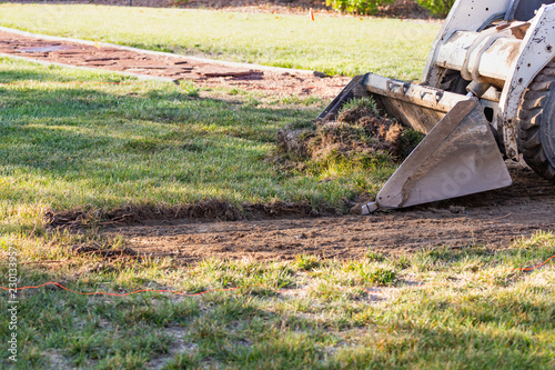 Small Bulldozer Removing Grass From Yard Preparing For Pool Installation