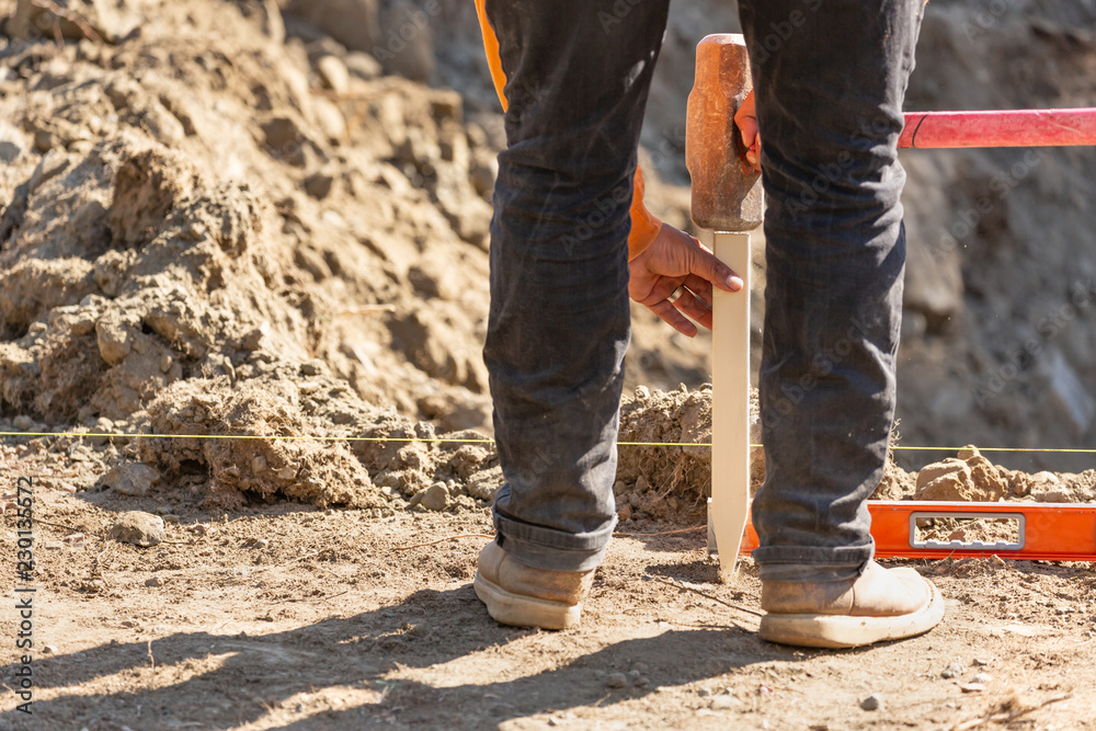 Worker Installing Stakes and Lumber Guides At Construction Site Worker Installing Stakes and Lumber Guides At Construction Site