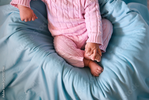 Close-up picture of baby holding her legs in her little armes