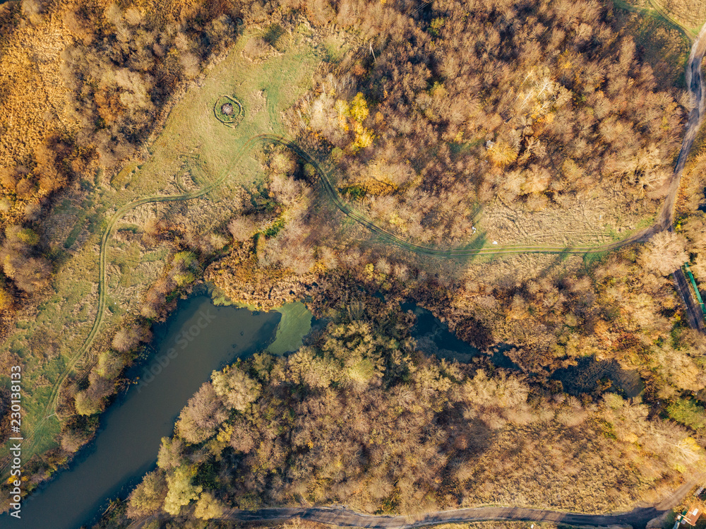 Top view from drone of colorful autumn trees and small lake