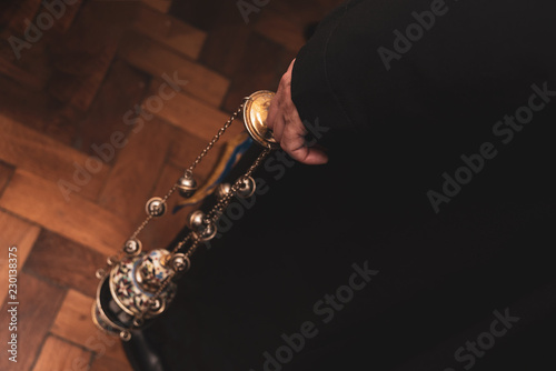 Priest in the church holds a cresset in one hand
