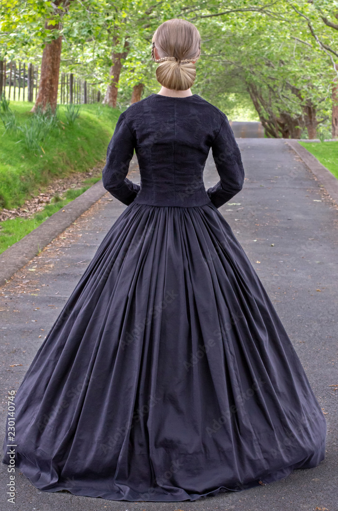 Fototapeta premium Victorian woman in black ensemble outdoors