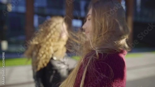 Close-up shot of a blonde and curly girfriends dancing to rhytmic music outdoor in early autumn. photo