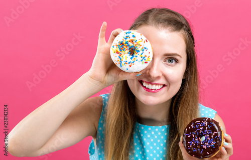 Young woman with donuts on a pink background