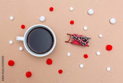 Cup of coffee with a miniature snow slide on a light brown paper background