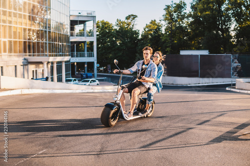 Lovely young couple driving electric bike. Modern city transportation photo