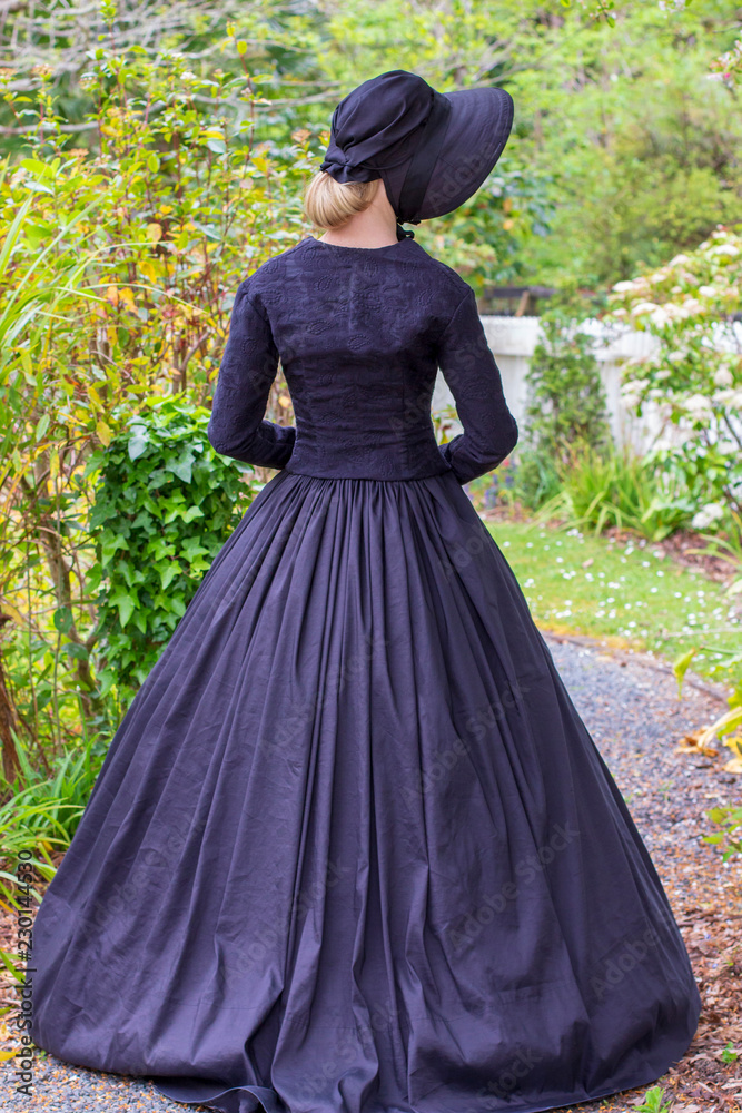 Fototapeta premium Victorian woman in black ensemble outdoors